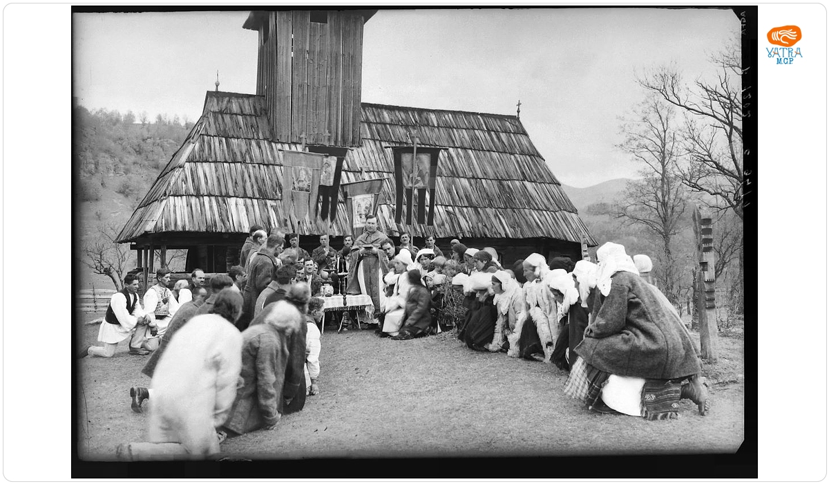 Grup de români la procesiune lângă biserica din lemn